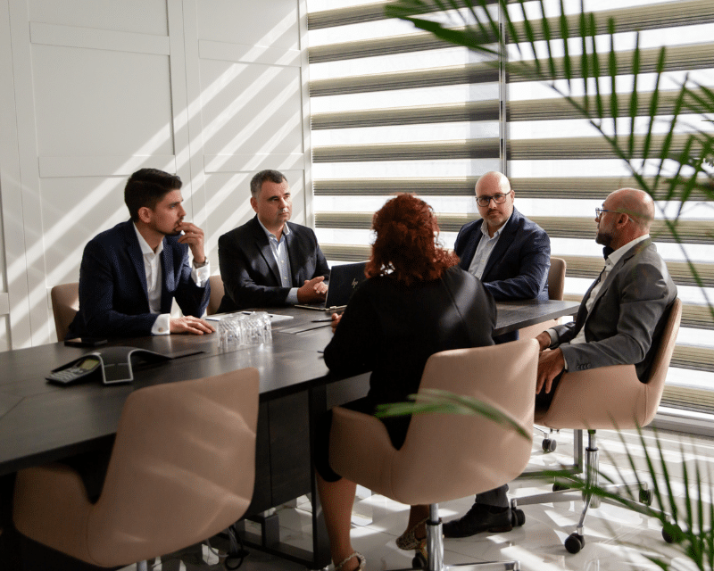 Partner at A2CO seated in the boardroom during a business meeting with colleagues.