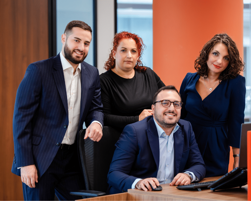 A2CO tax team in the office, with four team members posing together in professional business attire.