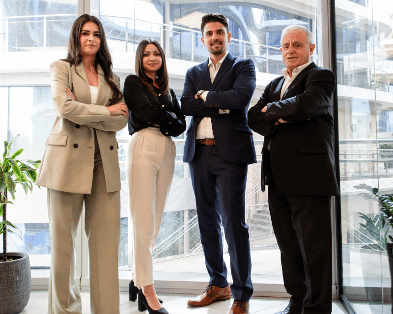 A2CO professionals standing confidently by the office window, representing the company’s corporate team.