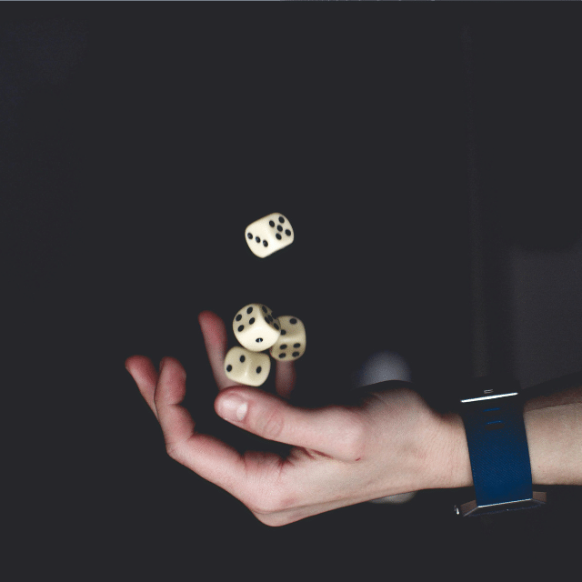 Hand tossing multiple dice in the air against a dark background