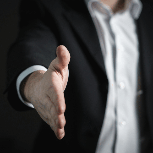 Businessman in a suit extending his hand forward for a handshake.